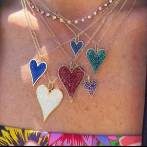 Close-up of layered gold heart necklaces featuring colorful glitter pendants and fine chains