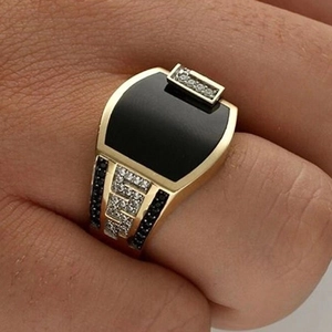 Macro view of gold signet ring with black stone and pave crystals on fingers