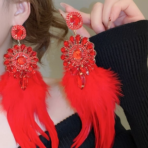 Gros plan de boucles d'oreilles en rubis avec monture dorée et glands en plumes rouges