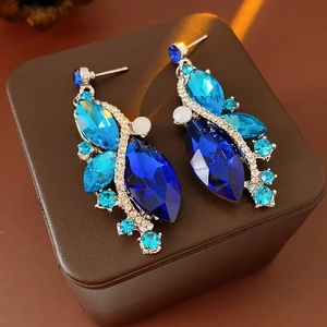 Detailed close-up of vintage rhinstone diamond-shaped earrings with blue crystals