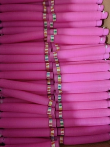 Close-up of numerous pink plastic pop tubes stacked neatly in a storage box