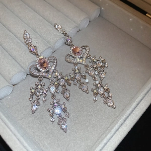 Macro shot of silver heart tassel earrings with pink stones and sparkling zircon details
