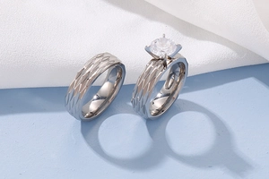 Macro detail of titanium steel couple rings with geometric scale pattern and crystal inlay