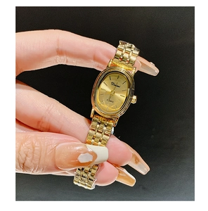 Close-up of elegant gold oval quartz watch for women with metal strap on black background