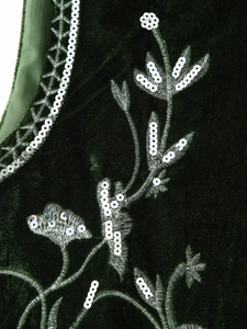 Close-up of silver floral embroidery and sequins on dark green velvet fabric