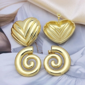 Polished 18k gold heart-shaped and spiral twisted hoop earrings on soft silk fabric