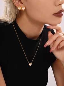 Detailed side view of model wearing gold heart necklace and earrings with white mother of pearl
