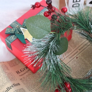 Macro detail of artificial pine needle Christmas wreath with red berries and gift box
