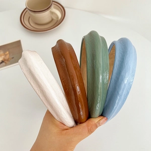 Detail showing four vintage leather headbands in white, brown, green, and blue colors