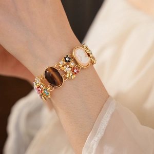 Close-up of vintage gold bracelet with relief cameo, enamel flowers and tiger eye stone