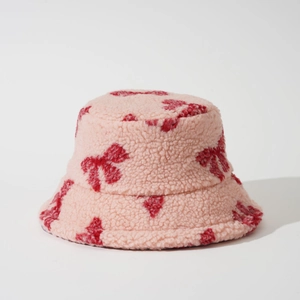 Close-up of pink lamb wool bucket hat with detailed red bow jacquard texture