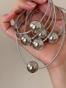 Detail shot of shiny silver beaded necklaces with tight snake chains and mirror finish