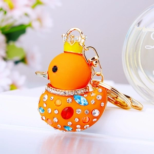 Macro shot of orange rhinestone rubber duck keychain with golden crown and sparkling gems