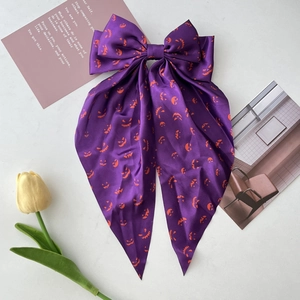 Detail of purple silk hair bow with orange pumpkin print and decorative cards