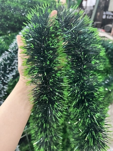 Close-up of 2m dark green Christmas tinsel garland with white tips for holiday decoration