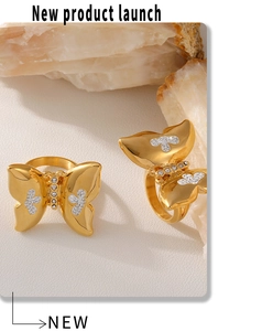 Detailweergave van twee gouden vlinderringen met witte diamanten op witte stenen