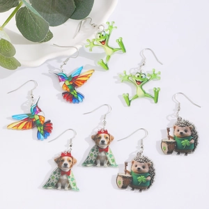 Detalle de pendientes de acrílico coloridos con diseños de colibrí y rana para festivos