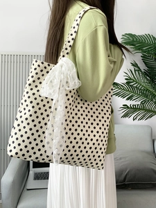Retro polka dot canvas tote bag with white lace bow detail worn by a model in a room