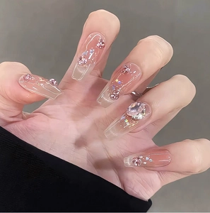 Detail of pink gradient press-on nails with 3D floral accents and shimmering crystals