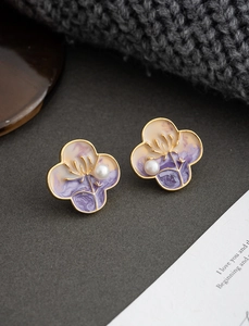 Macro detail of oil painting style clover earrings with purple texture and pearl inlay