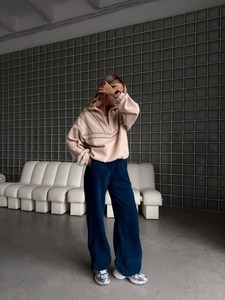 Sweat beige à demi-zip et pantalon large bleu marine porté par un mannequin