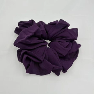 Detailed texture of purple chiffon scrunchie with soft elastic pleats on grey fabric