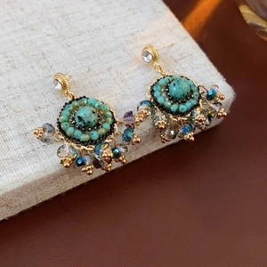 Dettaglio di orecchini vintage a fiore dorato con pietre turchesi e perle colorate