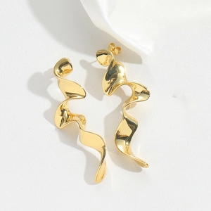 Close-up of elegant gold spiral drop earrings on white satin background with soft shadows