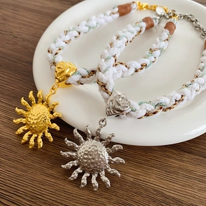 Close-up of bohemian woven sun pendant necklaces in gold and silver with hammer texture