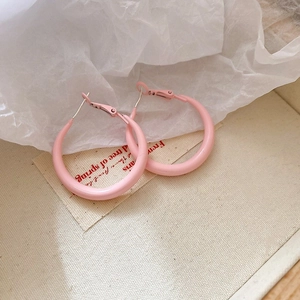 Close-up of pink matte round hoop earrings resting on elegant beige textured fabric
