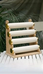 Detail of a 4-tier bamboo jewelry stand with white velvet bars and gold metal caps
