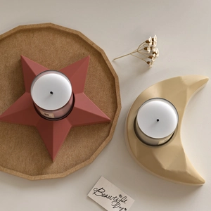 Star and moon shaped candle holders with scented glass candles in minimalist setting