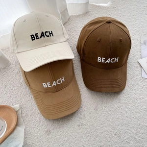 Detailed view of beach embroidery on three cotton baseball caps in earthy tones