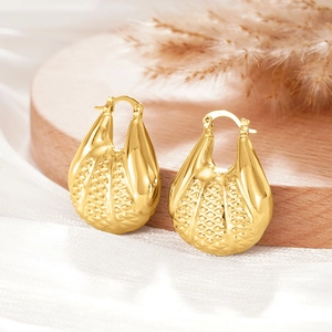 Détail de boucles d'oreilles dorées goutte d'eau avec texture de treillis sur bois