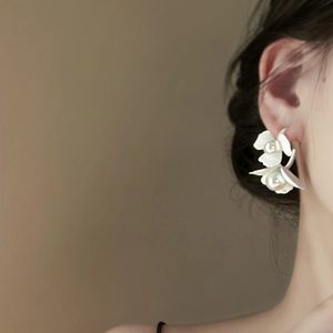 Elegant C-shaped white flower earrings with pearls on model, minimalist chic style