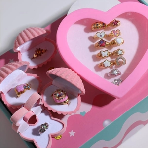 Close-up of golden children's rings set with colorful gems in pink heart-shaped gift box