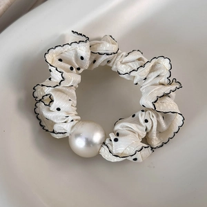 Detail of vintage polka dot scrunchie with glossy white pearl and scalloped edges