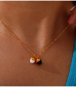 Close-up of gold-plated titanium necklace with two cute acorn pendants on a model