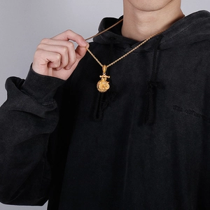 Detailed close-up of a golden hip-hop owl pendant on a twist chain worn by a male model