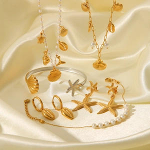 Close-up of golden ocean-themed jewelry set with starfish pendants and pearls on silk