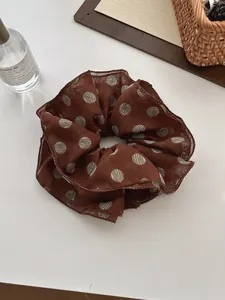 Detail of brown polka dot chiffon scrunchie with streamer and soft fabric texture
