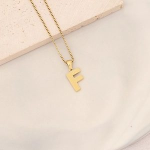 Detailed shot of gold-plated letter F pendant with honeycomb texture on a box chain