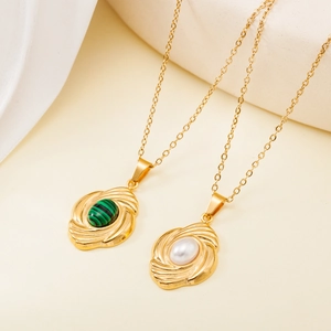 Detail of gold necklaces with shell pearl and green gemstone in swirl pendants