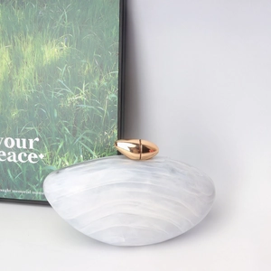 Detailed macro view of white marble acrylic evening bag with gold metal clasp
