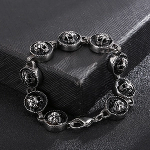 Detail of vintage lion head medallions on a men's steel bracelet with lobster clasp