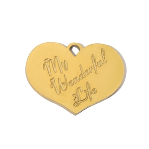 Macro detail of golden heart pendant engraved with My Wonderful Life on white background