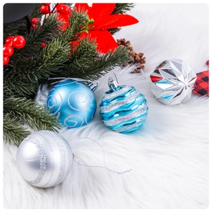 Close-up of blue and silver glitter patterned Christmas balls on white fur rug background