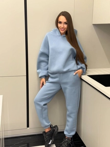 Relaxed light blue fleece hoodie and matching joggers set worn by a model in a kitchen