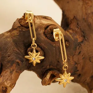 18K gold starburst drop earrings featuring white zircon inlay on vintage wooden stand