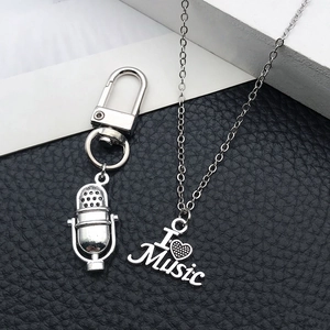 Close-up of silver microphone pendant and I Love Music heart necklace on leather